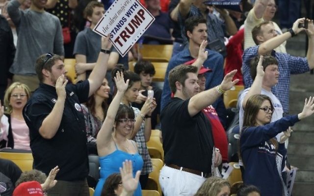 Le public lève le bras droit comme l'a demandé le candidat républicain Donald Trump pour promettre qu'ils voteront pour lui, pendant un évènement de campagne au CFE Arena, sur le campus de l'université de Floride, à Orlando, le 5 mars 2016. (Crédit : Joe Raedle/Getty Images/AFP)