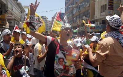 Des Palestiniens avec des affiches et des T-shirts représentant Dalal Mughrabi, une terroriste du Fatah responsable du massacre de la route côtière en 1978, qui a tué 38 Israéliens dont 13 enfants, pendant une manifestation à Ramallah, le 16 juillet 2008. (Crédit : Issam Rimawi/Flash90)