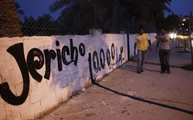 Des Palestiniens passant devant un mur peint en l'honneur des 10 000 ans de la ville de Jéricho en Cisjordanie (Crédit : Miriam Alster / FLASH90)