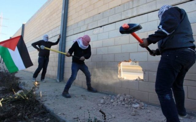 Des Palestiniens cassant la barrière de sécurité dans la ville de Bir Nabala, entre Jérusalem et Ramallah, en Cisjordanie, le 8 novembre 2014. (Crédit : STR/Flash90) Des Palestiniens cassant la barrière de sécurité dans la ville de Bir Nabala, entre Jérusalem et Ramallah, en Cisjordanie, le 8 novembre 2014. (Crédit : STR/Flash90)