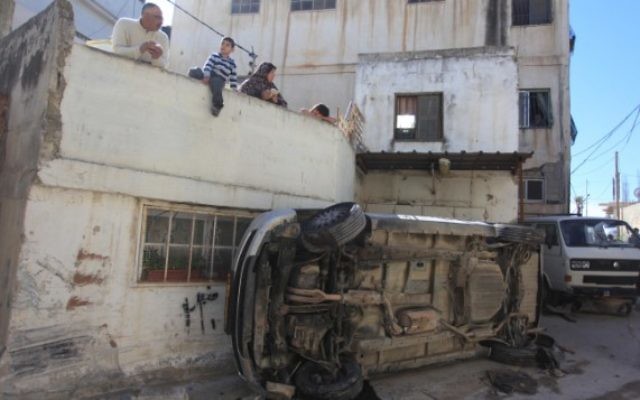 Des Palestiniens regardent les débris des affrontements entre les résidents du camp de réfugiés et les forces de sécurité israéliennes à Qalandiya, le 1er mars 2016. (Crédit : Flash90)