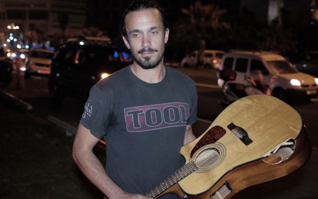 Yishay Montgomery tient la guitare endommagée qu'il a utilisée pour frapper Bashar Massalha lors de l'attaque terroriste à Jaffa le 8 mars 2016 (Crédit : Tomer Neuberg / Flash90)