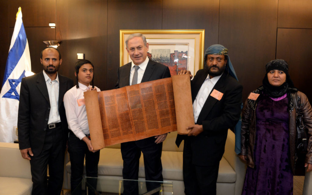 Le Premier ministre Benjamin Netanyahu avec un rouleau de Torah de plus de 500 ans avec certains des juifs yéménites qui sont arrivés en Israël dans le cadre d'une opération de sauvetage secrète, le 21 mars 2016. (Crédit : Haim Zach/GPO)