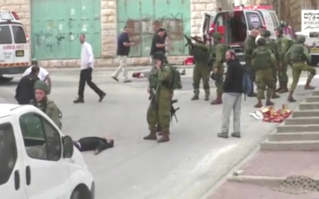 Un soldat israélien chargeant son arme avant de sembler tirer à la tête sur un terroriste palestinien au sol, apparemment désarmé, à la suite d'une attaque au couteau à Hébron, le 24 mars 2016. (Crédit : capture d'écran B'TSelem) Un soldat israélien chargeant son arme avant de sembler tirer à la tête sur un terroriste palestinien au sol, apparemment désarmé, à la suite d'une attaque au couteau à Hébron, le 24 mars 2016. (Crédit : capture d'écran B'TSelem)