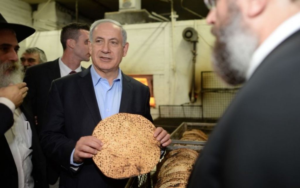 Le Premier ministre Benjamin Netanyahu avec une matzah shmoura dans une boulangerie de Kfar Chabad, en Israël, avant Pessah, le 1er avril 2014. (Crédit : Kobi Gideon/GPO/Flash90)