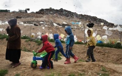 Des enfants bédouins israéliens de la tribu Tarabin jouent dans leur village bédouin non reconnu, près de la décharge de Dudaim (arrière-plan), près de la ville de Rahat, dans le sud du pays, le 7 février 2016. (Crédit : Menahem Kahana/AFP,) Des enfants bédouins israéliens de la tribu Tarabin jouent dans leur village bédouin non reconnu, près de la décharge de Dudaim (arrière-plan), près de la ville de Rahat, dans le sud du pays, le 7 février 2016. (Crédit : Menahem Kahana/AFP,)