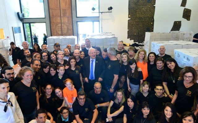 Le président Reuven Rivlin, entouré des volontaires de Leket Israël et de l'équipe du bureau du président, a participé à l'emballage de colis de nourriture pour Pessah, à la résidence présidentielle de Jérusalem, le 20 avril 2016. (Crédit : Kobi Gideon/GPO)