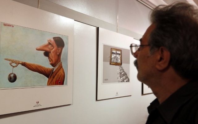 Un Iranien observe une caricature montrant Hitler, lors de la deuxième exposition internationale de dessins et caricatures sur l'Holocauste, à Téhéran, le 14 mai 2016. (Crédit : AFP/Atta Kenare) Un Iranien observe une caricature montrant Hitler, lors de la deuxième exposition internationale de dessins et caricatures sur l'Holocauste, à Téhéran, le 14 mai 2016. (Crédit : AFP/Atta Kenare)