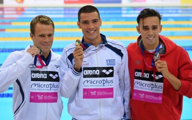 Le médaillé d'or grec, Andreas Vazaios (au centre) pose pour une photo avec le médaillé d'argent israélien Gal Nevo (à gauche) et le médaillé de bronze portugais, Alexis Manacas Santos (à droite) après la finale homme du 200 mètres nage libre individuel aux Championnats d'Europe de natation à Londres, le 18 mai 2016 (Crédit : AFP PHOTO / GLYN KIRK) Le médaillé d'or grec, Andreas Vazaios (au centre) pose pour une photo avec le médaillé d'argent israélien Gal Nevo (à gauche) et le médaillé de bronze portugais, Alexis Manacas Santos (à droite) après la finale homme du 200 mètres nage libre individuel aux Championnats d'Europe de natation à Londres, le 18 mai 2016 (Crédit : AFP PHOTO / GLYN KIRK)