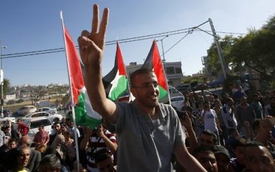 Le journaliste palestinien emprisonné, Mohammed al-Qiq, fait le symbole de la victoire alors qu'il arrive dans son village de Dura, au sud de la Cisjordanie, après avoir été libéré de la prison israélienne de Nafha, le 19 mai 2016 (Crédit : AFP/ HAZEM BADER)