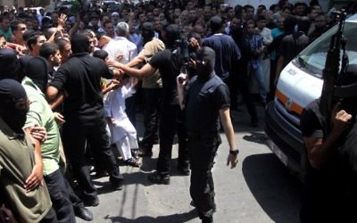Un Palestinien armé et masqué repousse une foule de croyants devant la mosquée de Gaza Ville après la prière du vendredi, avant l'exécution de 18 hommes qui auraient collaboré avec Israël, le 22 août 2O14. (Crédit : AFP) Un Palestinien armé et masqué repousse une foule de croyants devant la mosquée de Gaza Ville après la prière du vendredi, avant l'exécution de 18 hommes qui auraient collaboré avec Israël, le 22 août 2O14. (Crédit : AFP)