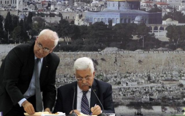 Le président de l'Autorité palestinienne, Mahmoud Abbas (à droite) et le responsable des négociations pour la paix, Saeb Erekat, signent une candidature pour intégrer les organismes de l'ONU, à Ramallah, en Cisjordanie, le mardi 1er avril 2014. (Crédit : Issam Rimawi/Flash90)