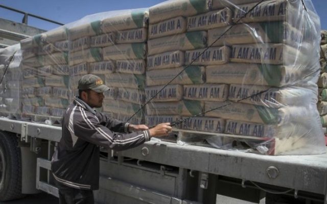 Un Palestinien ajuste les sacs de ciment chargés sur un camion après leur entrée dans le sud de la bande de Gaza depuis Israël, via le poste-frontière Keren Shalom à Rafah, le 29 avril 2015. (Crédit : Abed Rahim Khatib /Flash 90)