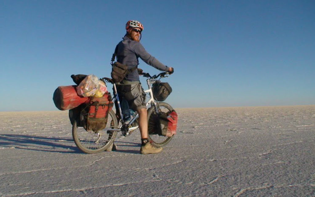 Sadan traversant les marais salants sur Emuna, son vélo hybride Thorn bleu et blanc, lors de son voyage autour du monde de 2007 à 2011 (Crédit : autorisation Roei Sadan).