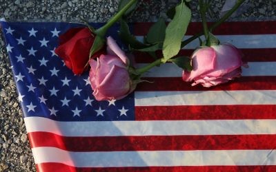 Des roses et un drapeau américain posés sur l sol près du Pulse, le club d'Orlando où Omar Mateen a tué 49 personnes et en a blessé 53, le 13 juin 2016. (Crédit : Joe Raedle/Getty Images/AFP)
