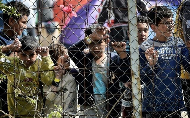 Des enfants derrière une clôture, dans le camp pour migrants de Moria, transformé par la police en centre de détention, à Mytilene, sur l'île de Lesbos, en Grèce, le 3 avril 2016. (Crédit : Aris Messinis/AFP)