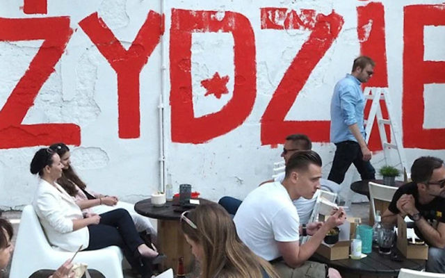 Des gens mangeant au restaurant israélien Jaffa à Lodz, en Pologne -avec le mot 'Juif' en arrière-plan le 11 juin 2016. (Autorisation de Rafal Betlejewski / via JTA) Des gens mangeant au restaurant israélien Jaffa à Lodz, en Pologne -avec le mot 'Juif' en arrière-plan le 11 juin 2016. (Autorisation de Rafal Betlejewski / via JTA)