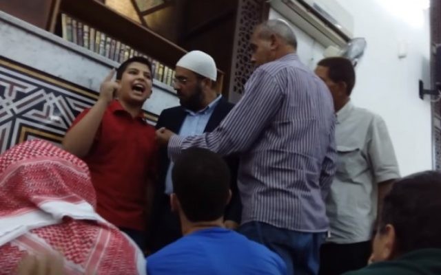 Abd Al-Aziz Al-Saifi, enfant autoproclamé prêcheur, pendant une de ses diatribes contre Israël dans une mosquée de Jordanie, alors que plusieurs hommes essaient de le persuader de se taire. (Crédit : capture d'écran YouTube) Abd Al-Aziz Al-Saifi, enfant autoproclamé prêcheur, pendant une de ses diatribes contre Israël dans une mosquée de Jordanie, alors que plusieurs hommes essaient de le persuader de se taire. (Crédit : capture d'écran YouTube)