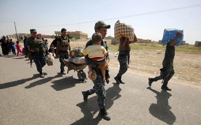 Des membres des forces irakiennes aident les civils à atteindre un point militaire pendant qu'ils fuient les violences de Saqlawiyah, village au nord ouest de Fallouja, le 3 juin 2016. (Crédit : AFP PHOTO/AHMAD AL-RUBAYE) Des membres des forces irakiennes aident les civils à atteindre un point militaire pendant qu'ils fuient les violences de Saqlawiyah, village au nord ouest de Fallouja, le 3 juin 2016. (Crédit : AFP PHOTO/AHMAD AL-RUBAYE)