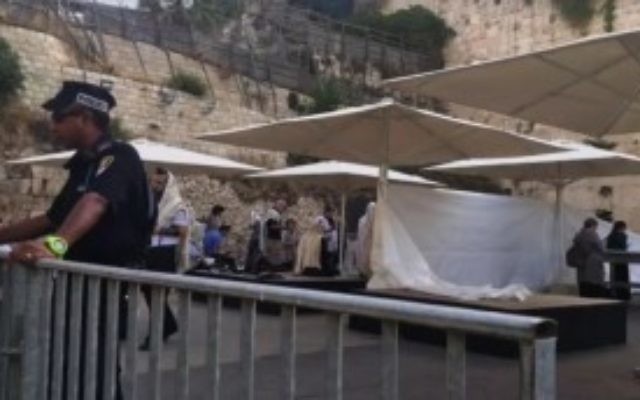 Un policier se tient devant une cloison de fortune érigée devant un office de prière orthodoxe à l'esplanade égalitaire du mur Occidental, le 14 juin 2016 (Capture d'écran: Facebook)