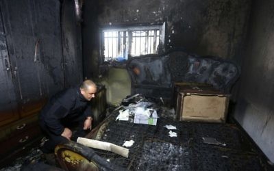 Un policier palestinien inspecte les dégâts à l'intérieur d'une maison incendiée appartenant à un témoin clé d'un incendie criminel perpétré par des extrémistes juifs qui ont tué une famille palestinienne, dans le village de Duma, en Cisjordanie, après l'incendie qui a éclaté dans la maison aux premières heures du 20 mars 2016. (AFP/Jaafar Ashtiyeh)