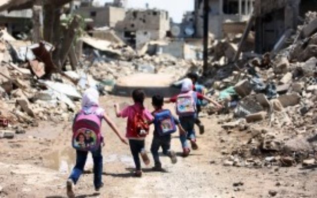 Des enfants syriens scolarisés passent devant des immeubles en ruine  à Jobar, fief rebelle, en banlieue est de la capitale Damas, le 30 avril 2016. (Crédit : AFP/Amer Almohibany)