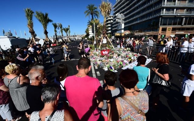 Les gens déposent des fleurs, des bougies et des messages à un mémorial improvisé à Nice le 16 juillet 2016, en hommage aux victimes de l'attaque du 14 juillet sur la promenade des Anglais, qui a tué au moins 84 personnes et fait des centaines de blessés. (Crédit : Giuseppe Cacace/AFP) Les gens déposent des fleurs, des bougies et des messages à un mémorial improvisé à Nice le 16 juillet 2016, en hommage aux victimes de l'attaque du 14 juillet sur la promenade des Anglais, qui a tué au moins 84 personnes et fait des centaines de blessés. (Crédit : Giuseppe Cacace/AFP)