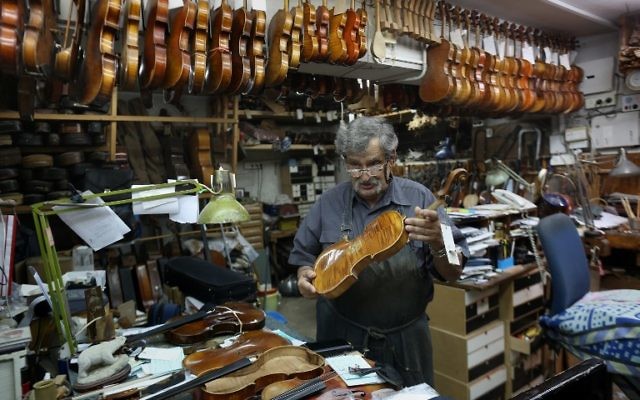 Le luthier israélien Amnon Weinstein montre un violon de sa collection de violons restaurés qui étaient auparavant la propriété de Juifs européens pendant l'Holocauste dans son atelier à Tel Aviv le 15 juillet 2016. (Crédit : AFP / MENAHEM KAHANA) Le luthier israélien Amnon Weinstein montre un violon de sa collection de violons restaurés qui étaient auparavant la propriété de Juifs européens pendant l'Holocauste dans son atelier à Tel Aviv le 15 juillet 2016. (Crédit : AFP / MENAHEM KAHANA)
