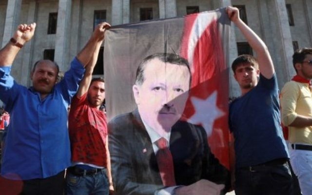 Des partisans du président turc Recep Tayyip Erdogan tiennent une bannière avec son portrait pendant un rassemblement devant le parlement turc, réuni en session extraordinaire à la suite d'une tentative de coup d'Etat, à Ankara, le 16 juillet 2016. (Crédit : AFP/Adem Altan) Des partisans du président turc Recep Tayyip Erdogan tiennent une bannière avec son portrait pendant un rassemblement devant le parlement turc, réuni en session extraordinaire à la suite d'une tentative de coup d'Etat, à Ankara, le 16 juillet 2016. (Crédit : AFP/Adem Altan)
