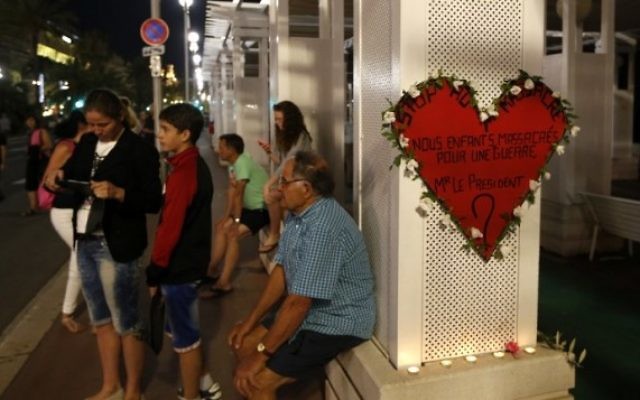 Un homme près d'un panneau en forme de cœur sur lequel il est inscrit : "Stop au massacre... Nos enfants massacrés pour une guerre... M. le Président ?" sur la Promenade des Anglais, à Nice, le 17 juillet 2016. (Crédit : AFP/Valéry Hache) Un homme près d'un panneau en forme de cœur sur lequel il est inscrit : "Stop au massacre... Nos enfants massacrés pour une guerre... M. le Président ?" sur la Promenade des Anglais, à Nice, le 17 juillet 2016. (Crédit : AFP/Valéry Hache)