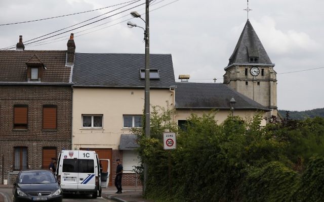 Les policiers montent la garde derrière l'église Saint-Etienne de Saint-Etienne-du-Rouvray le 26 Juillet 2016, suite à une attaque par deux hommes armés de couteaux. (Crédit : CHARLY TRIBALLEAU/AFP)