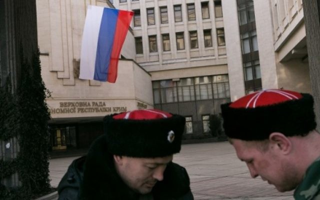Un Russe et un volontaire cosaque de Crimée devant le parlement régional de Crimée, où flotte le drapeau russe, à Simferopol, le 14 mars 2014. (Crédit : AFP/Daniel Leal Olivas) Un Russe et un volontaire cosaque de Crimée devant le parlement régional de Crimée, où flotte le drapeau russe, à Simferopol, le 14 mars 2014. (Crédit : AFP/Daniel Leal Olivas)