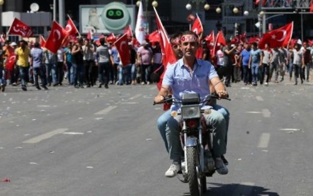 Deux hommes sur une mobylette pendant une manifestation entre la place Kizilay et le bâtiment de l'Etat-major turc à Ankara, à la suite d'une tentative de coup d'Etat, le 16 juillet 2016. (Crédit : AFP/Adem Altan) Deux hommes sur une mobylette pendant une manifestation entre la place Kizilay et le bâtiment de l'Etat-major turc à Ankara, à la suite d'une tentative de coup d'Etat, le 16 juillet 2016. (Crédit : AFP/Adem Altan)
