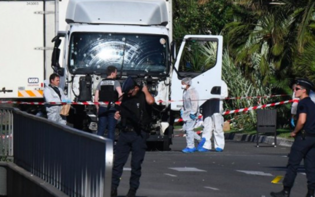 Des officiers et des policiers cherchent des preuves à proximité du camion utilisé sur la promenade des Anglais dans la ville Côte d'Azur de Nice le 15 juillet 2016, pour tuer une foule d'individus venue admirer le feu d'artifices  (Crédit : AFP/ANNE-CHRISTINE POUJOULAT)
