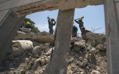 Des soldats des unités de recherche et sauvetage du Commandement de la Défense passive de l'armée israélienne nettoient des débris d'une fausse frappe de roquette pendant un exercice à grande échelle, à Zikim, près de la frontière de la bande de Gaza, le 3 juillet 2016. (Crédit : unité des porte-paroles de l'armée israélienne) Des soldats des unités de recherche et sauvetage du Commandement de la Défense passive de l'armée israélienne nettoient des débris d'une fausse frappe de roquette pendant un exercice à grande échelle, à Zikim, près de la frontière de la bande de Gaza, le 3 juillet 2016. (Crédit : unité des porte-paroles de l'armée israélienne)