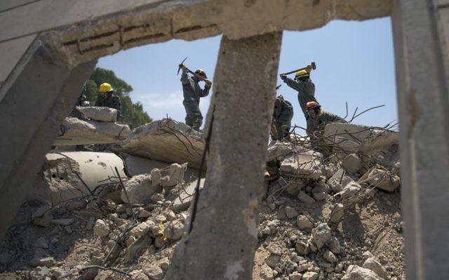 Des soldats des unités de recherche et sauvetage du Commandement de la Défense passive de l'armée israélienne nettoient des débris d'une fausse frappe de roquette pendant un exercice à grande échelle, à Zikim, près de la frontière de la bande de Gaza, le 3 juillet 2016. (Crédit : unité des porte-paroles de l'armée israélienne)