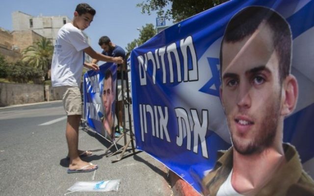 Le frère du soldat israélien décédé Oron Shaul organise une manifestation devant la résidence du premier ministre Benjamin Netanyahu à Jérusalem, le 30 juin 2016. Les panneaux disent "Rendez Oron". (Crédit : Yonatan Sindel/Flash90) Le frère du soldat israélien décédé Oron Shaul organise une manifestation devant la résidence du premier ministre Benjamin Netanyahu à Jérusalem, le 30 juin 2016. Les panneaux disent "Rendez Oron". (Crédit : Yonatan Sindel/Flash90)