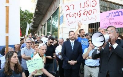 Le grand rabbin d'Efrat Shlomo Riskin parle dans un mégaphone, le 6 juillet 2016, lors d'une manifestation devant les bureaux du grand rabbin de Jérusalem, en soutien aux conversions du rabbin new-yorkais Haskel Lookstein, sous l’œil attentif du chef de l'Agence juive Natan Sharansky et de l'ancien député Dov Lipman (Crédit : Ezra Landau)