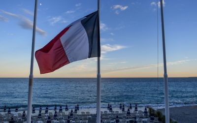 Drapeau français en berne devant une plage vide de la Promenade des Anglais à Nice, au lendemain d'un attentat qui a fait 84 morts, le 15 juillet 2016. (Crédit : David Ramos/Getty Images via JTA)
