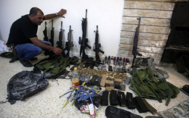 Un membre des forces de l'ordre palestinienne présente des armes que la police a trouvé pendant la recherche de deux hommes armés, toujours en fuite, au poste de police de Naplouse en Cisjordanie, le 21 août 2016. (Crédit : AFP/Jaafar Ashtiyeh) Un membre des forces de l'ordre palestinienne présente des armes que la police a trouvé pendant la recherche de deux hommes armés, toujours en fuite, au poste de police de Naplouse en Cisjordanie, le 21 août 2016. (Crédit : AFP/Jaafar Ashtiyeh)