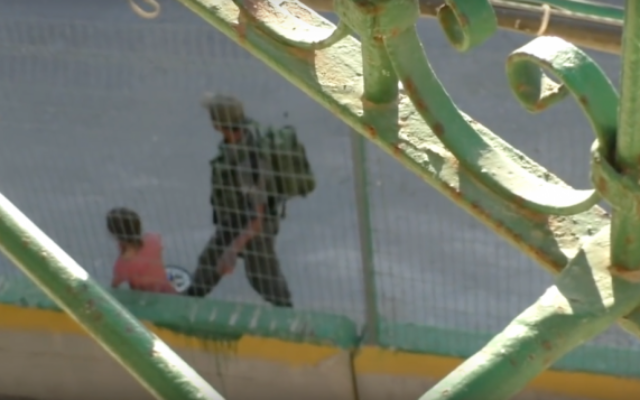 Dans une vidéo diffusée par l'organisation de gauche des droits de l'Homme B'Tselem, un officier de la police aux frontières s'empare du vélo d'une fillette palestinienne de 8 ans, avant qu'un autre officier ne le jette dans un buisson à proximité, à Hébron, le 25 juillet 2016 (Crédit : capture d'écran B'Tselem) Dans une vidéo diffusée par l'organisation de gauche des droits de l'Homme B'Tselem, un officier de la police aux frontières s'empare du vélo d'une fillette palestinienne de 8 ans, avant qu'un autre officier ne le jette dans un buisson à proximité, à Hébron, le 25 juillet 2016 (Crédit : capture d'écran B'Tselem)