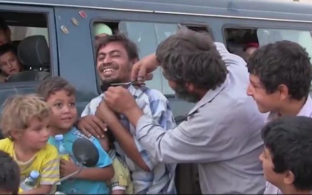 Un Syrien coupe la barbe d'un autre Syrien après que sa ville de Manbij a été libéré du contrôle de l'Etat islamique, le 13 août 2016 (Crédit : Capture d'écran / K24) Un Syrien coupe la barbe d'un autre Syrien après que sa ville de Manbij a été libéré du contrôle de l'Etat islamique, le 13 août 2016 (Crédit : Capture d'écran / K24)