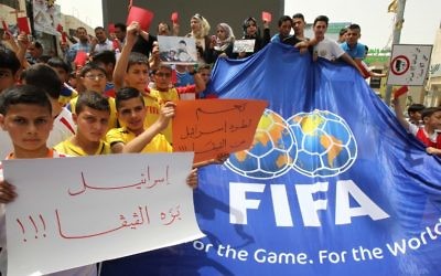 De jeunes Palestiniens avec des cartons rouges et des pancartes "Israël en-dehors de la FIFA" pendant une manifestation contre la Fédération israélienne de football à Hébron, en Cisjordanie, le 28 mai 2015. (Crédit : AFP/Hazem Bader)