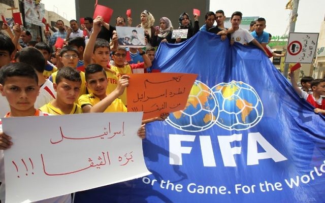De jeunes Palestiniens avec des cartons rouges et des pancartes "Israël en-dehors de la FIFA" pendant une manifestation contre la Fédération israélienne de football à Hébron, en Cisjordanie, le 28 mai 2015. (Crédit : AFP/Hazem Bader) De jeunes Palestiniens avec des cartons rouges et des pancartes "Israël en-dehors de la FIFA" pendant une manifestation contre la Fédération israélienne de football à Hébron, en Cisjordanie, le 28 mai 2015. (Crédit : AFP/Hazem Bader)