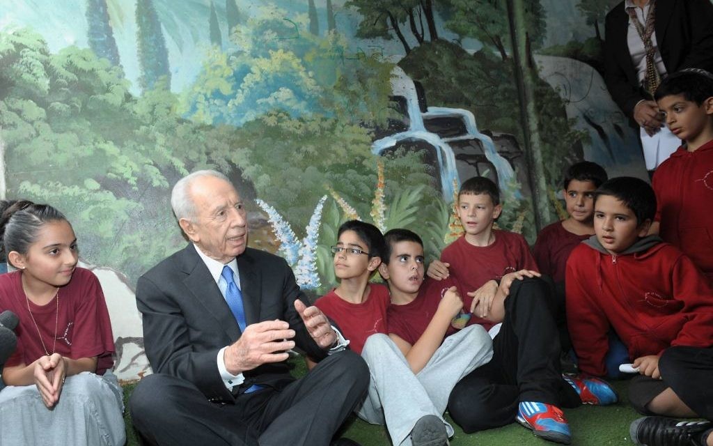 Shimon Peres, alors président, avec les enfants de Sderot dans un abri anti-bombes pendant l'opération Bordure protectrice, à l'été 2014. (Crédit : GPO)