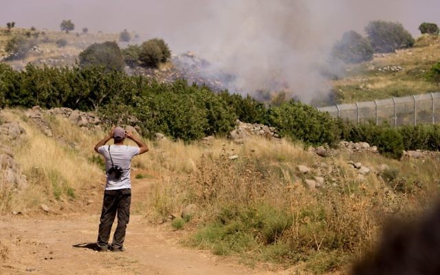 Un Druze regarde les bombardements entre les forces syriennes depuis la partie israélienne du plateau du Golan, le 16 juin 2015. (Crédit : Basel Awidat/Flash90)