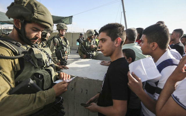 Des soldats israéliens en train de contrôler l'identité palestiniens au checkpoint de Qalandia entre la ville de Ramallah en Cisjordanie et Jérusalem, le 1er juillet 2016 (Crédit : Flash90) Des soldats israéliens en train de contrôler l'identité palestiniens au checkpoint de Qalandia entre la ville de Ramallah en Cisjordanie et Jérusalem, le 1er juillet 2016 (Crédit : Flash90)