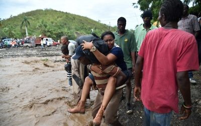Des habitants de Haïti traversent la rivière La Digue, à Petit Goave, où le pont s'est effondré à cause de la pluie apportée par l'ouragan Matthew, au sud ouest de Port-au-Prince, le 6 octobre 2016. (Crédit : AFP/Hector Retamal)