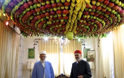 Le grand prêtre Samaritain, Abdullah Wassef Tawfiq, se tient avec son frère Husney Cohen dans son salon avec une « succah » fait maison à base de fruits frais pour la fête des Tabernacles ou Souccot, sur le mont Garizim près de la ville de Naplouse en Cisjordanie , le 18 Octobre, 2016 (Crédit : Dov Lieber / Times of Israel)