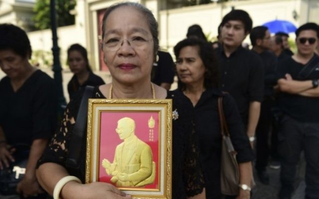 Une femme tient une représentation du Roi thaïlandais Bhumibol Adulyadej, dans la queue pour rendre hommage au Grand Palais à Bangkok le 14 octobre 2016 (Crédits : AFP/Munir Uz Zaman) Une femme tient une représentation du Roi thaïlandais Bhumibol Adulyadej, dans la queue pour rendre hommage au Grand Palais à Bangkok le 14 octobre 2016 (Crédits : AFP/Munir Uz Zaman)